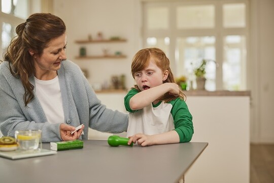 Kind sitzt neben der Mutter und hustet