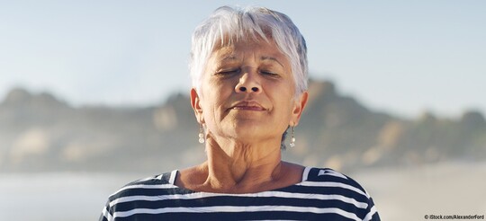 Ältere Frau mit grauen Haaren in der Natur die scheinbar einmal tief und richtig durchatmet