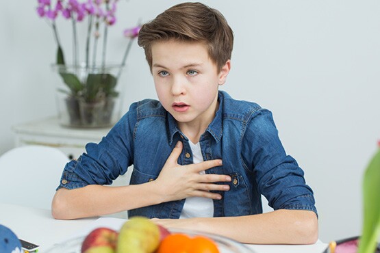 Junge mit Engegefühl im Brustkorb, welches ein Symptom von Asthma bronchiale sein kann